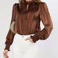 Women’s brown blouse styled with white pants for an elegant look.
