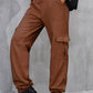 Side profile of brown high-waist cargo pants with functional pockets.
