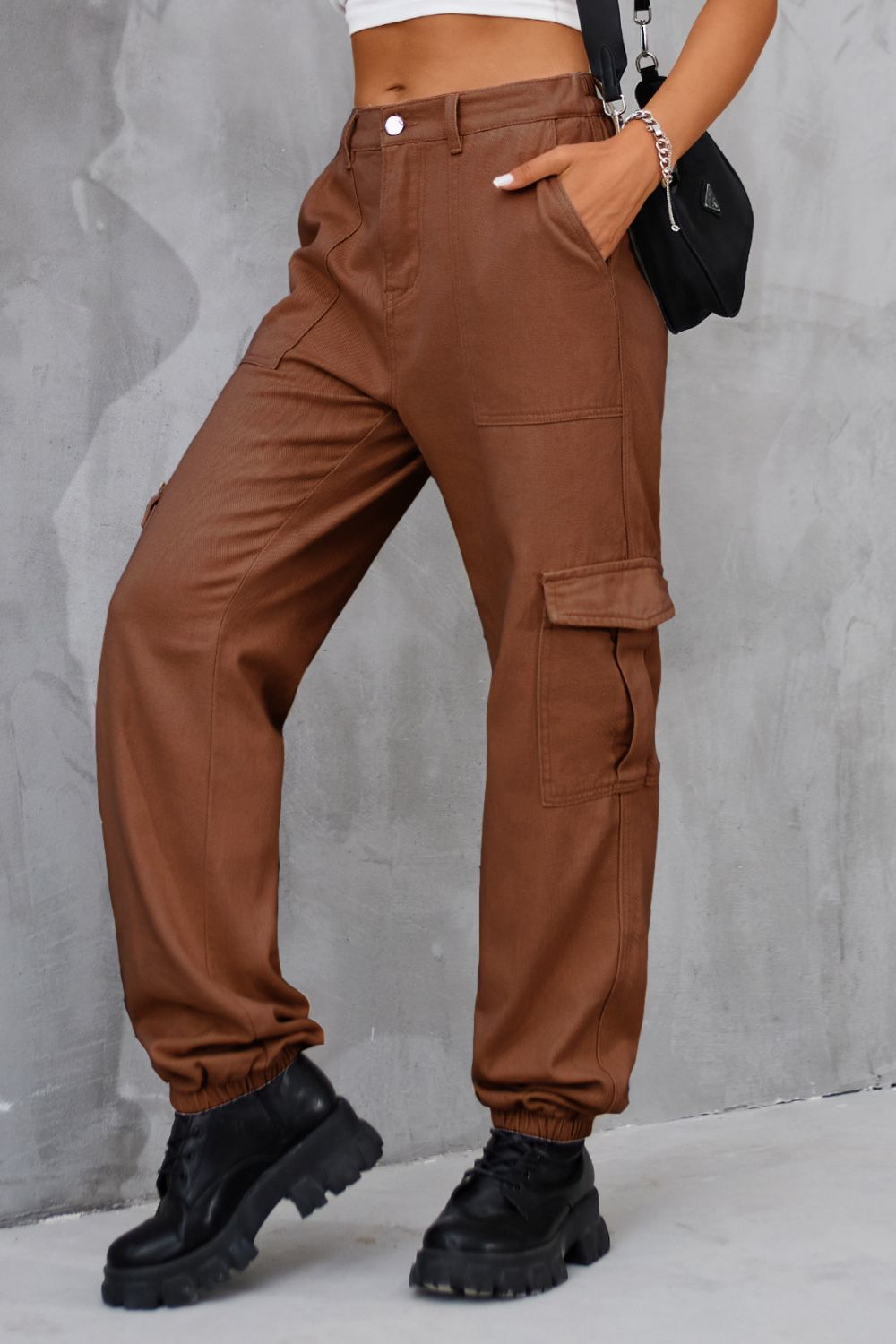 Side profile of brown high-waist cargo pants with functional pockets.
