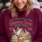 Festive burgundy sweatshirt with gingerbread house graphic, perfect for the holidays.