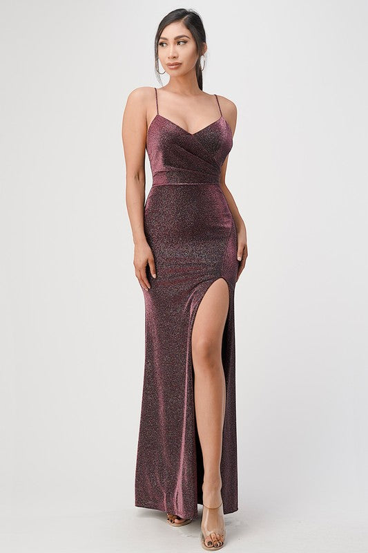 Model in a burgundy mermaid gown with spaghetti straps and a side slit, front view.
