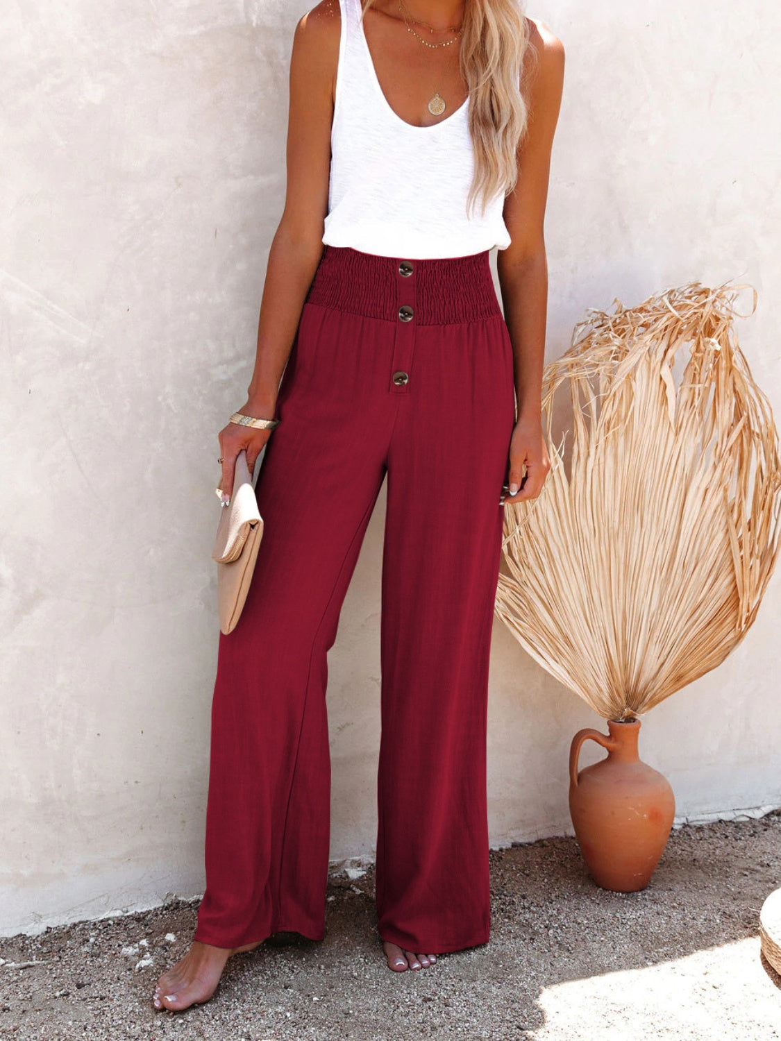 Burgundy high-waisted wide-leg pants with a decorative button detail for a chic look.