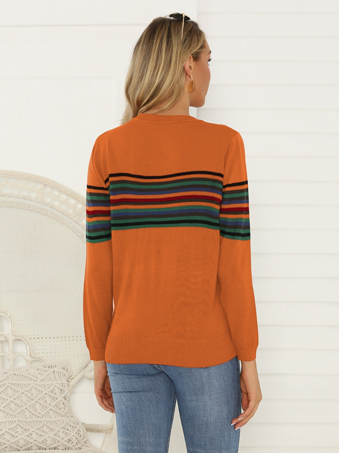 Woman styling a retro-inspired burnt orange striped sweater with jeans
