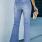 Back view of button-fly distressed raw hem flare jeans in light blue denim with a high waist and frayed hem.