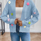 Blue cardigan adorned with pink, yellow, green, and purple knitted flowers.