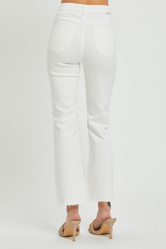 High-rise white jeans featuring knee rips and multiple button closure.