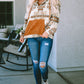 Woman in southwestern aztec hoodie paired with ripped jeans
