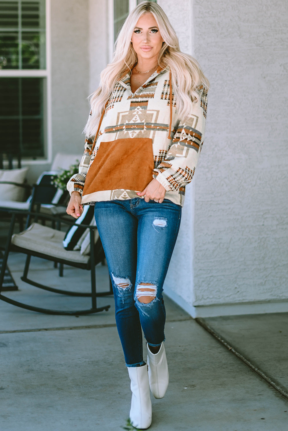 Woman in southwestern aztec hoodie paired with ripped jeans
