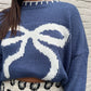 Casual blue knit sweater featuring a bow design, perfect for cozy and casual winter days.

