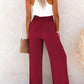 Burgundy high-waisted wide-leg pants with a decorative button detail for a chic look.