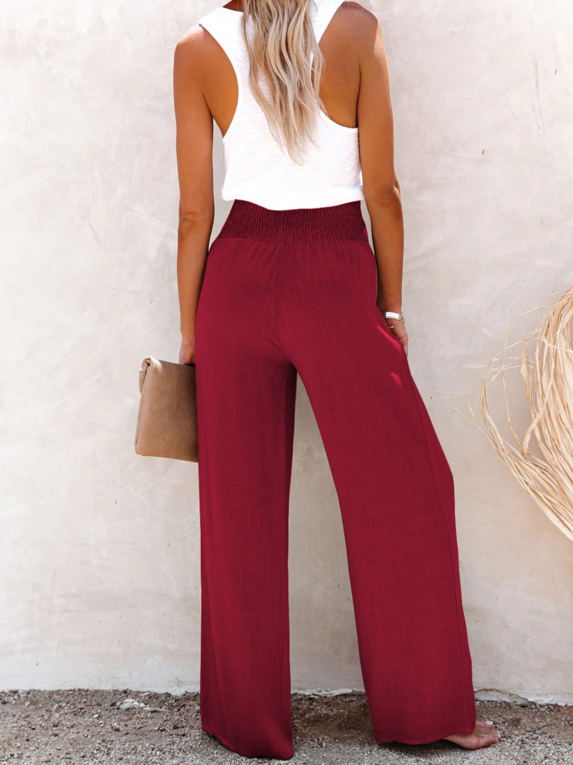 Burgundy high-waisted wide-leg pants with a decorative button detail for a chic look.