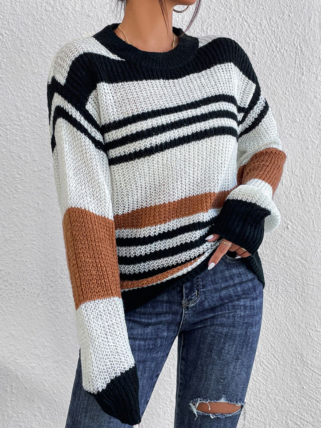 Woman in a relaxed-fit striped sweater with black and orange tones