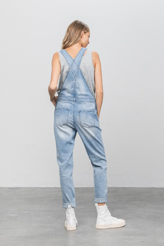 Casual destroyed light wash overalls with ripped details and side button closures.
