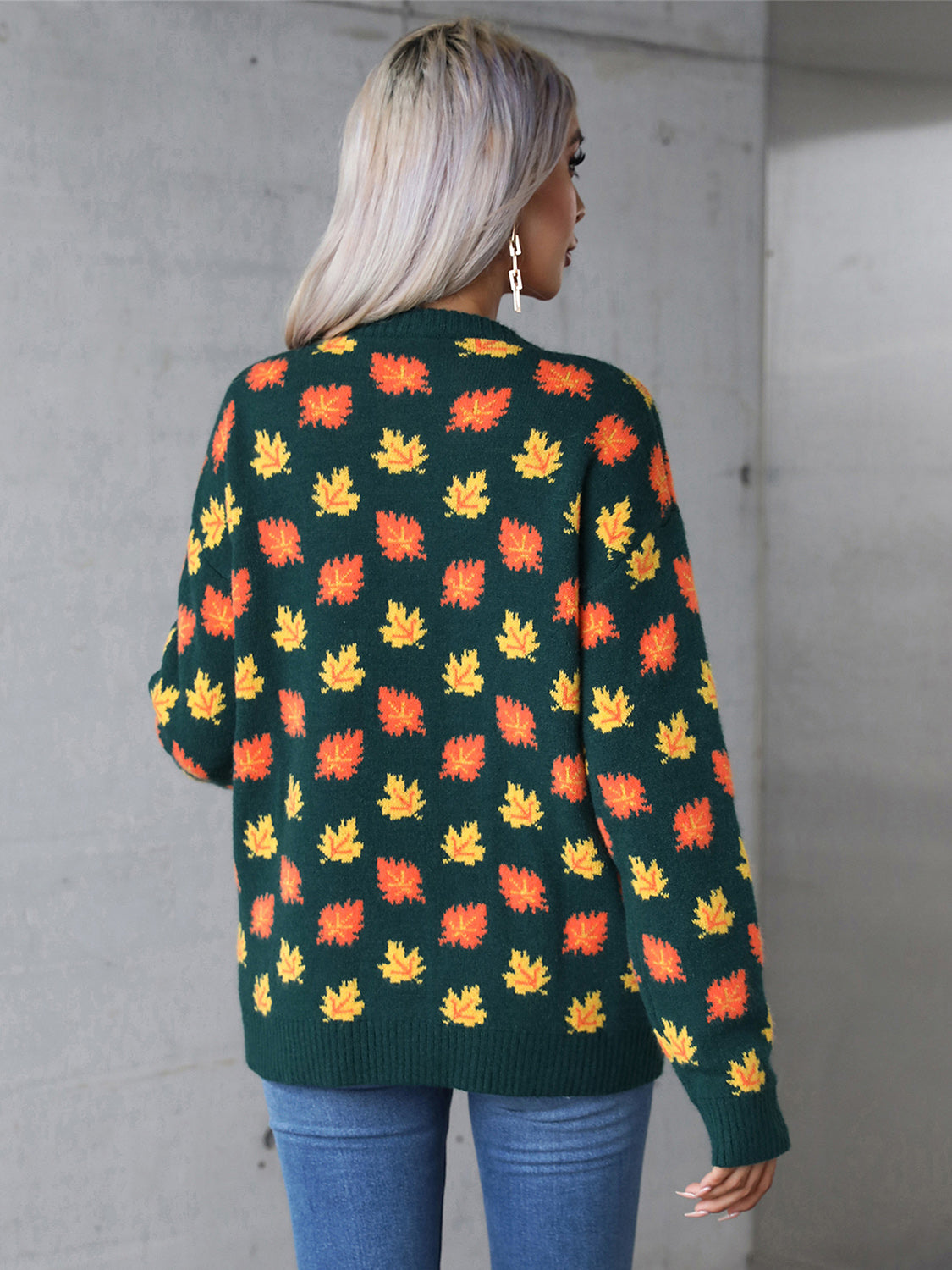 Casual green sweater adorned with orange fall leaves, great for cozy autumn days.
