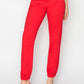 Casual red high-waisted jogger jeans styled with clear heels for an everyday look.
