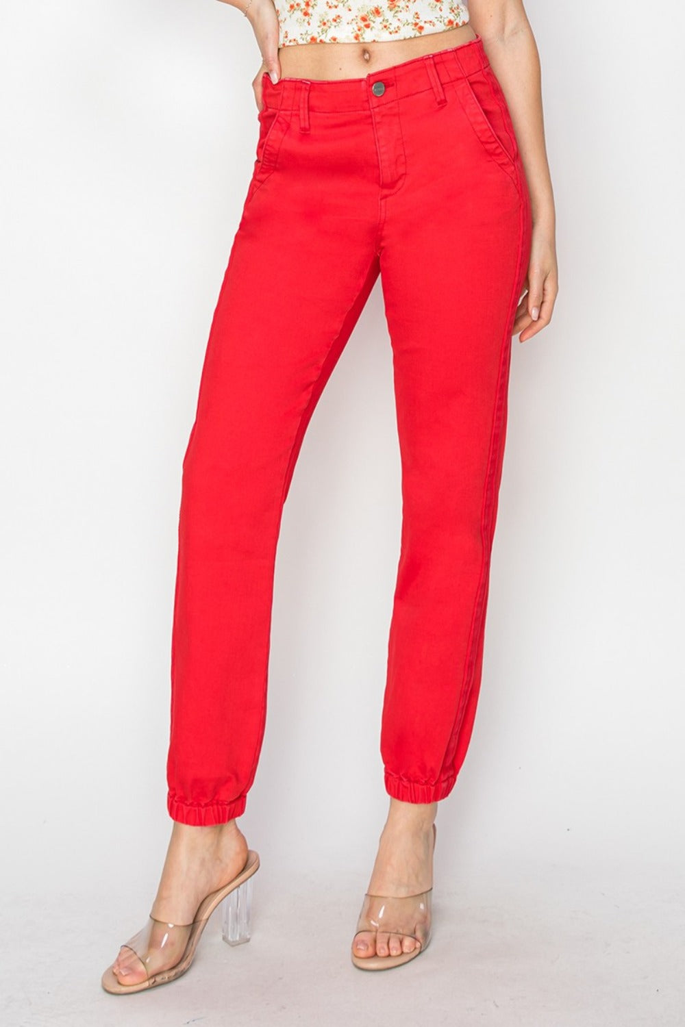 Casual red high-waisted jogger jeans styled with clear heels for an everyday look.
