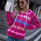 Pink tie-dye hoodie with a fun, multicolored pattern, paired with casual jeans for a laid-back look.
