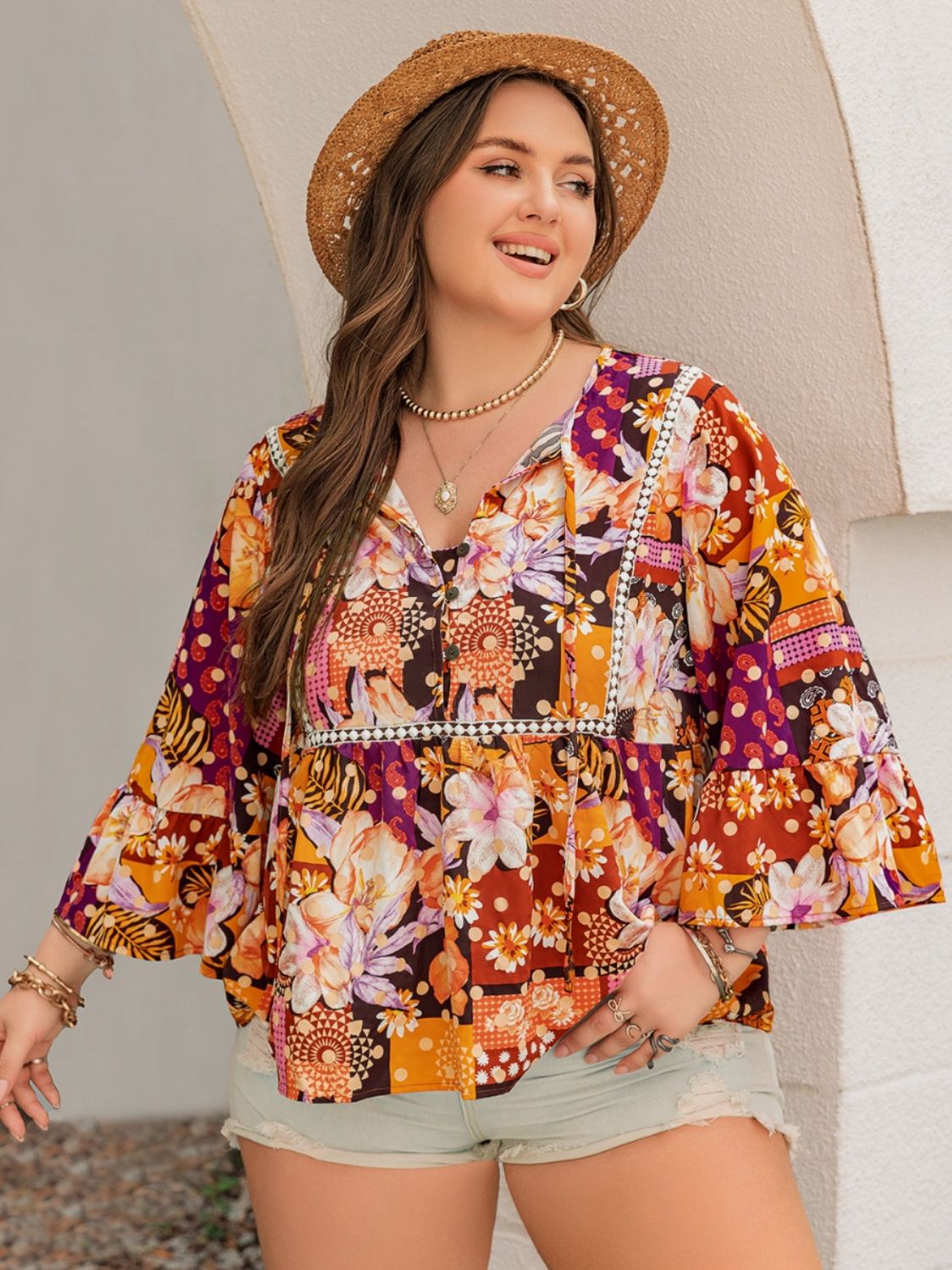 Orange floral blouse with lace detailing, styled with shorts.
