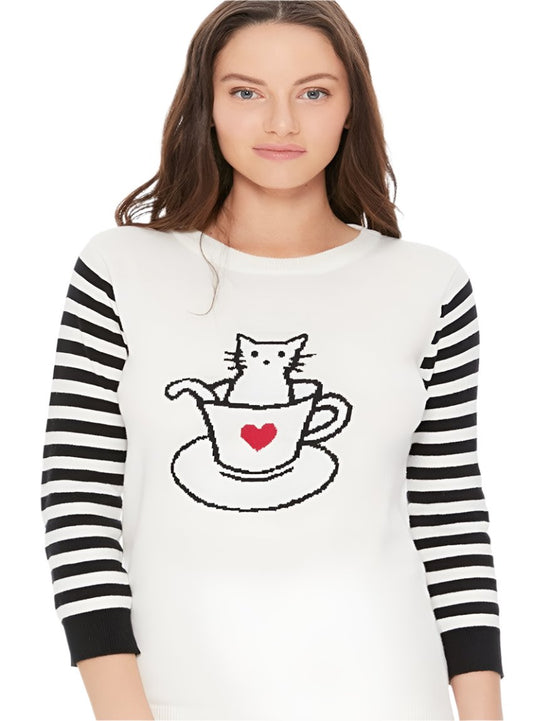 Close-up of a cozy sweater with a jacquard cat in a cup design and striped sleeves.
