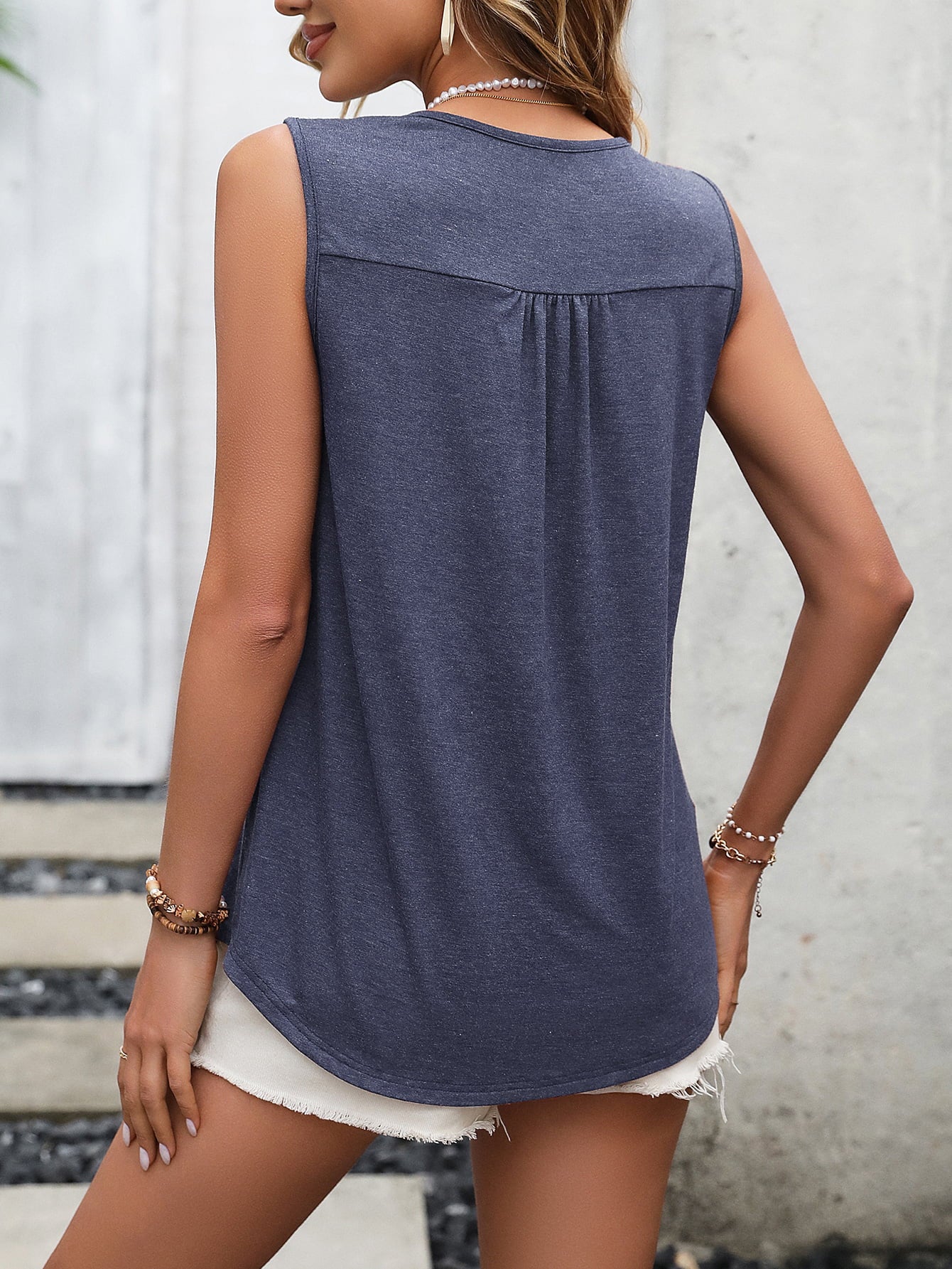 Elegant sleeveless top in blue with lace and buttons.