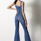 Flare leg denim jumpsuit with front button detailing and adjustable straps.
