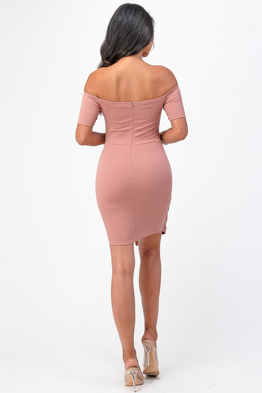 Elegant pink bodycon dress with a twist detail and off-shoulder neckline, perfect for any event.
