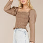 Casual smocking top styled with high-waisted jeans for an effortless look.





