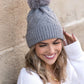 Soft chunky knit gray winter hat with a natural faux fur pom accent
