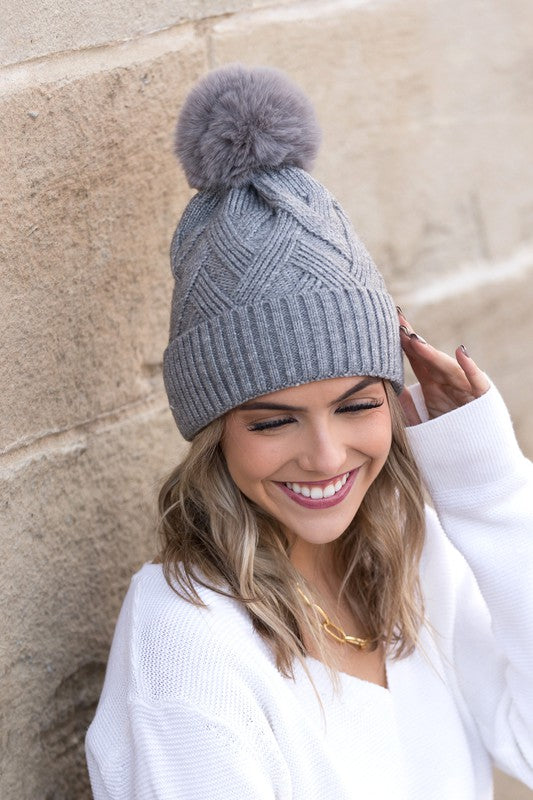 Soft chunky knit gray winter hat with a natural faux fur pom accent
