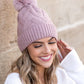 Mauve knit beanie featuring a chunky design and faux fur pom detail
