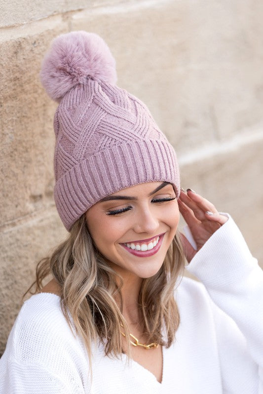 Mauve knit beanie featuring a chunky design and faux fur pom detail
