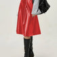 Close-up of red faux leather skirt, showing smooth finish and A-line shape.
