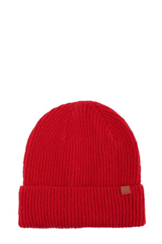 Minimalist red winter hat with ribbed knit texture and a leather tab accent.
