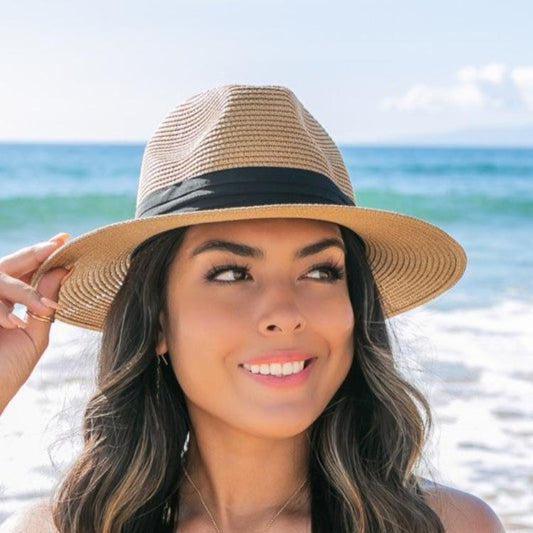 Woman wearing a classic straw fedora with a black band at the beach.