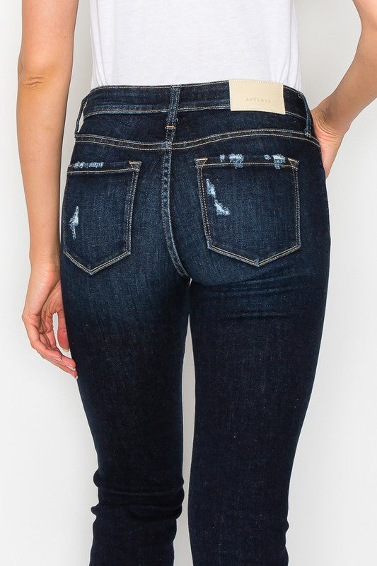 Close-up of distressed detailing on plus-size dark wash jeans.