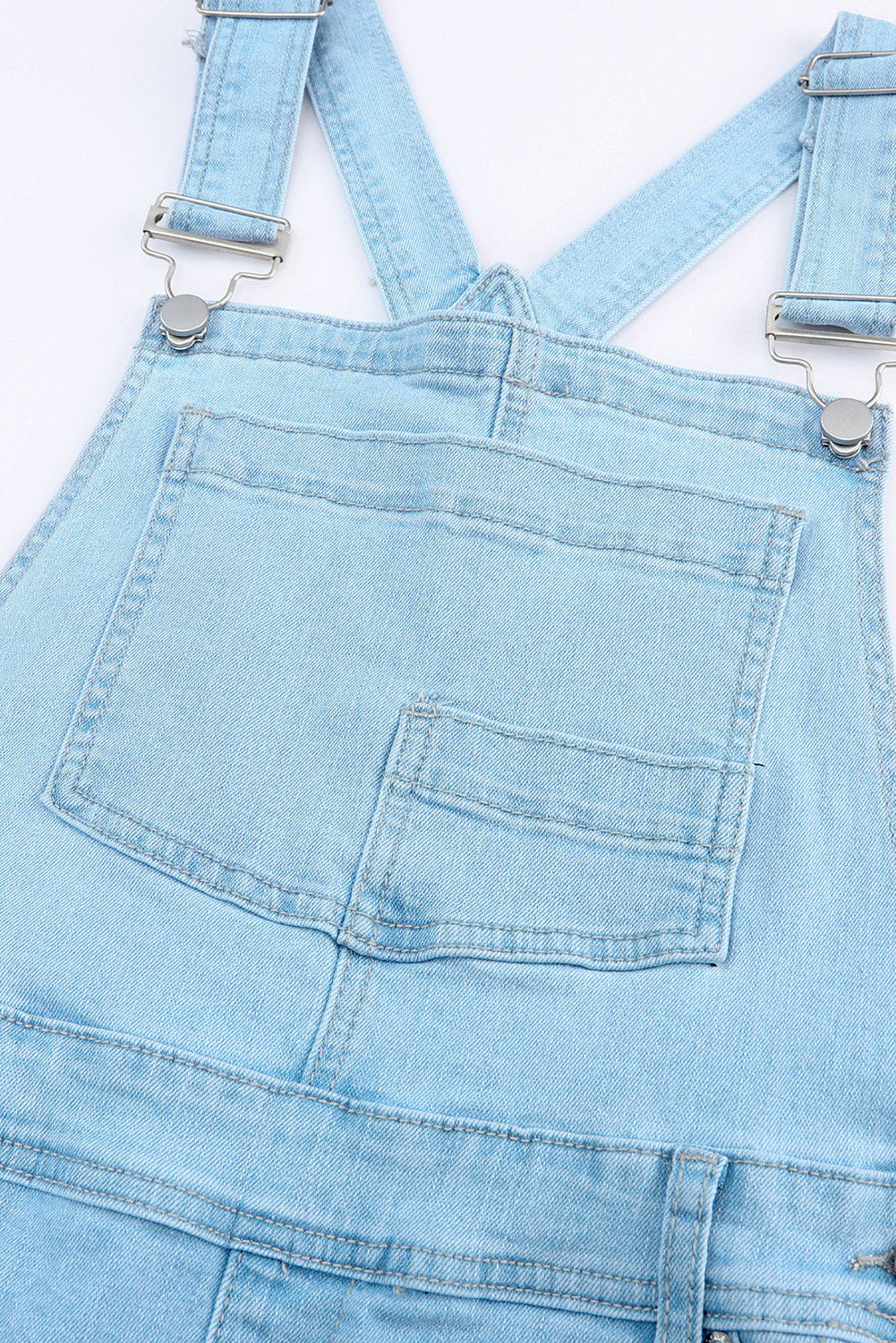 Edgy distressed denim overalls paired with a casual white tank top.
