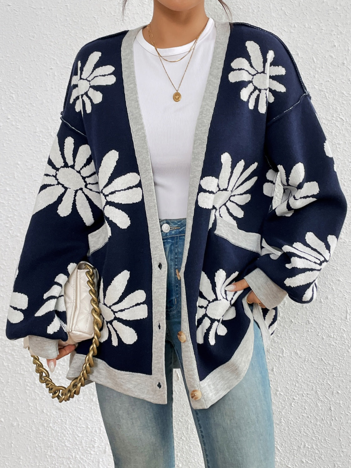 Woman showcasing a relaxed-fit floral cardigan in soft knit fabric, navy with white flowers.
