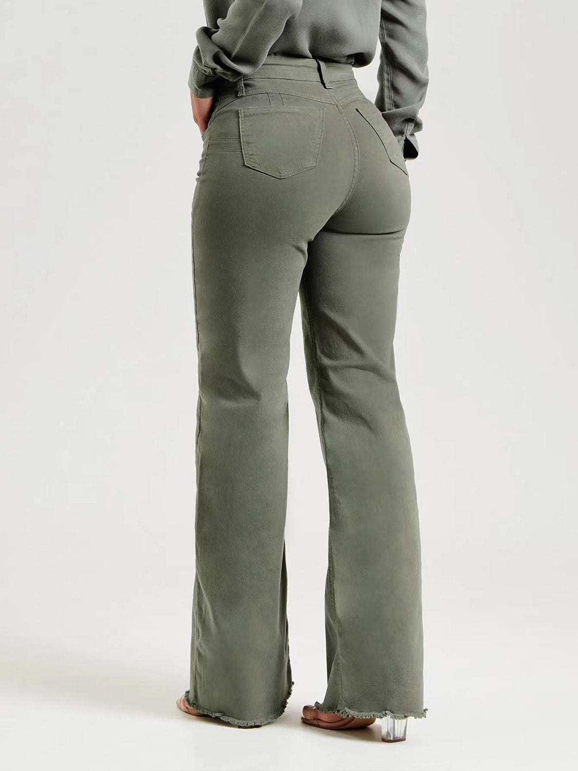 Rear view of green straight leg raw hem jeans showing back pockets.