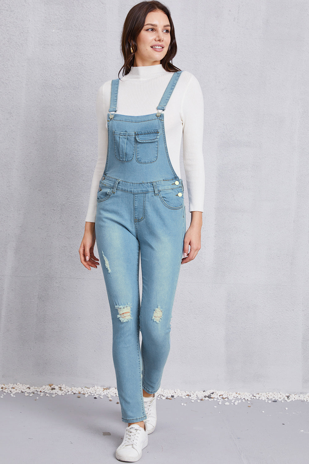 Comfortable pocketed distressed denim light wash overalls in a relaxed, everyday fit.
