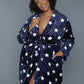 Woman wearing a belted navy plush robe with a star pattern, styled for loungewear.
