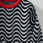 Close-up of the soft, cozy fabric on the black wavy stripe sweater, ideal for colder days.

