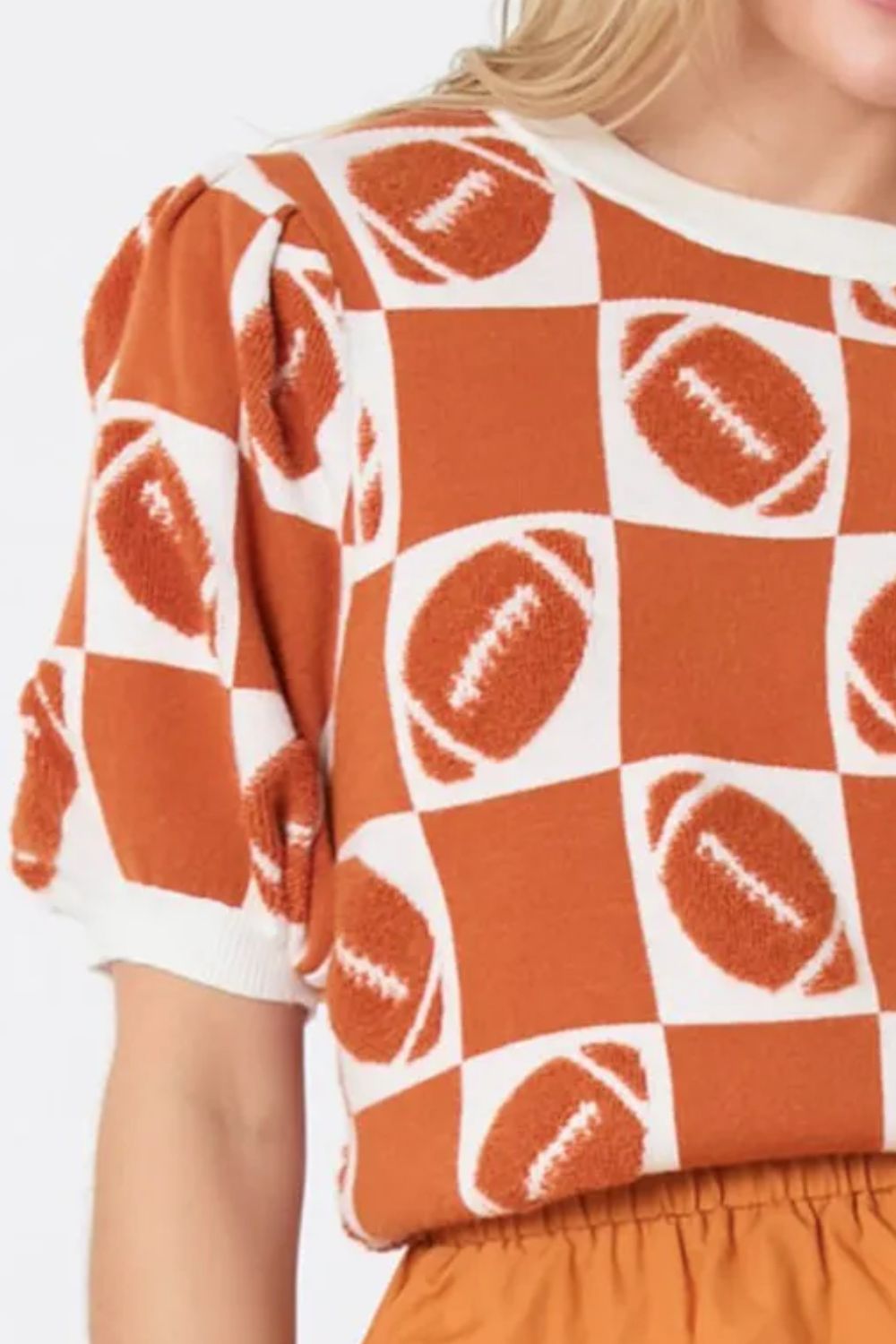 Game day puff sleeve sweater featuring a football-themed checkerboard pattern in orange and white.