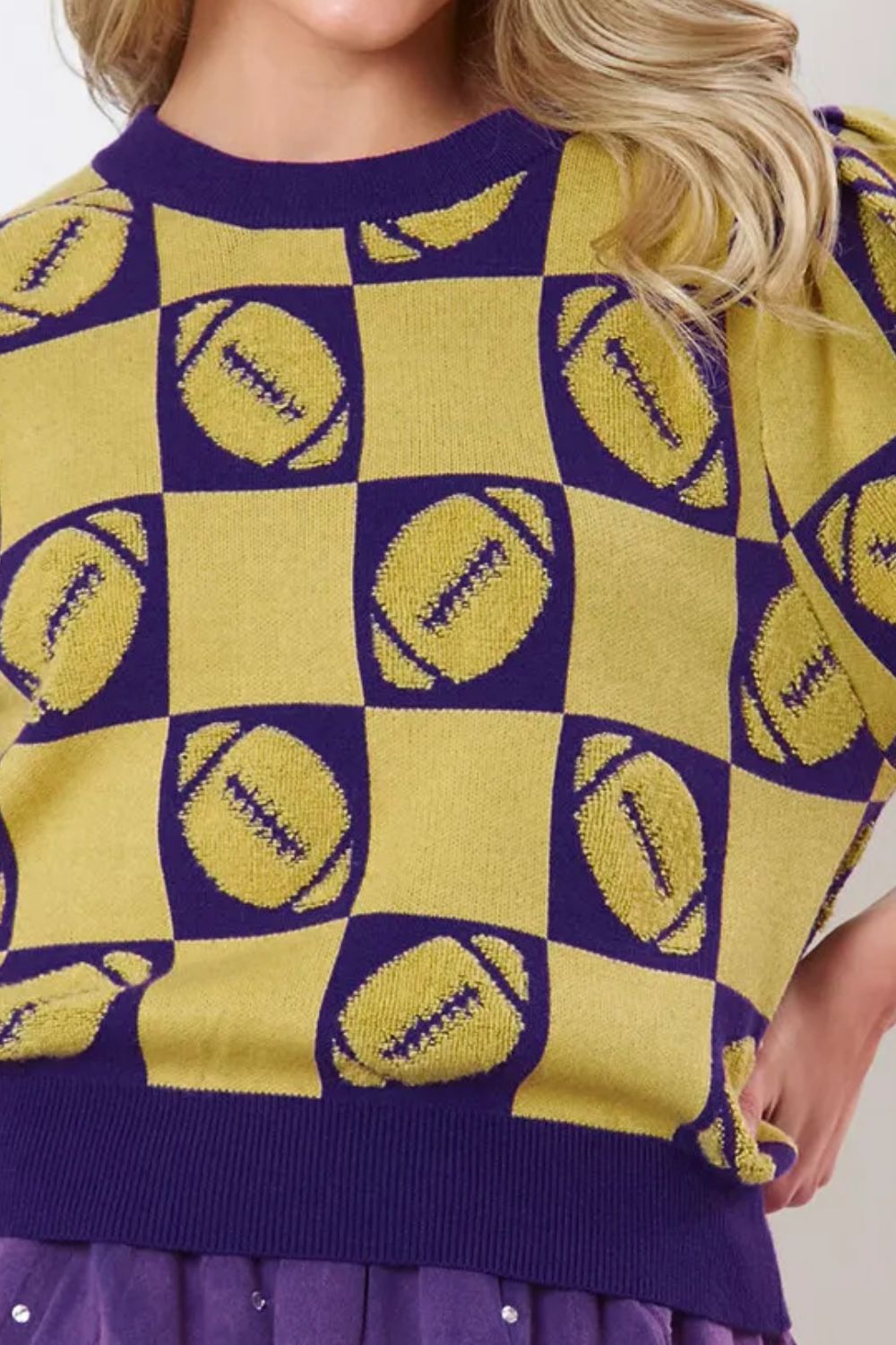 Close-up of a gold and purple checkerboard football sweater with puff sleeves.