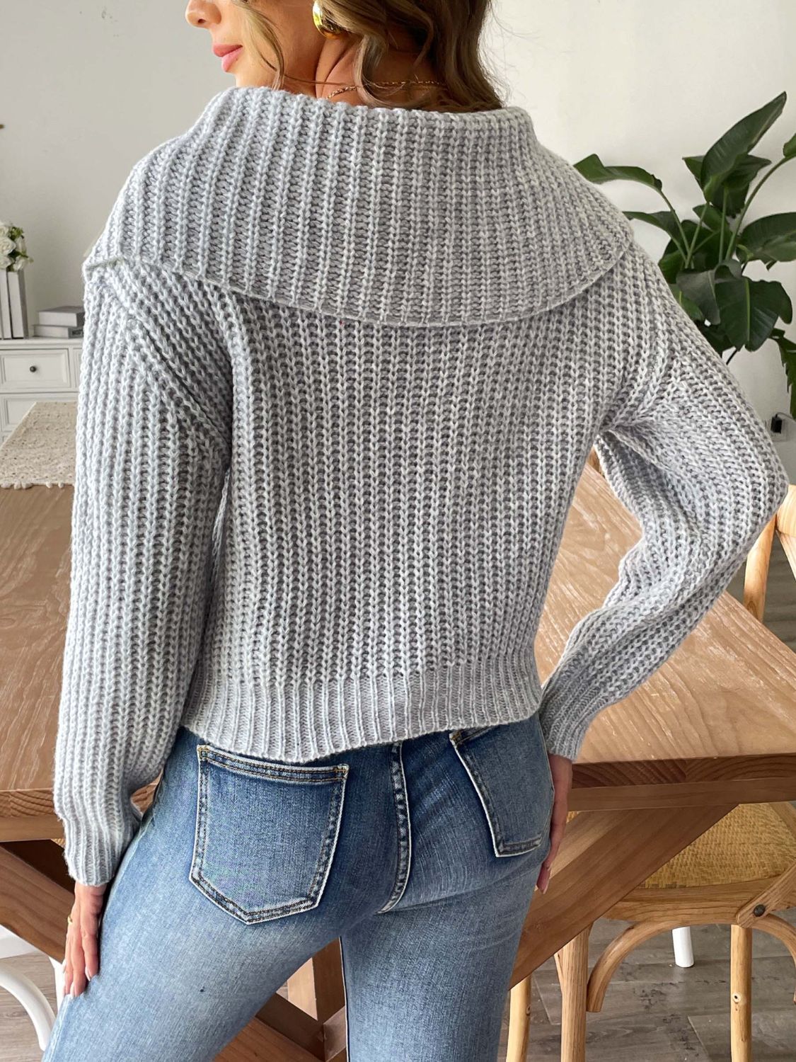 Woman wearing a soft gray wide-collar sweater, perfect for layering.
