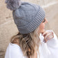 Soft chunky knit gray winter hat with a natural faux fur pom accent
