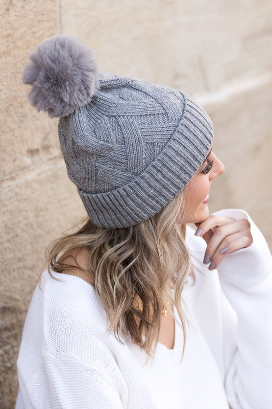 Soft chunky knit gray winter hat with a natural faux fur pom accent
