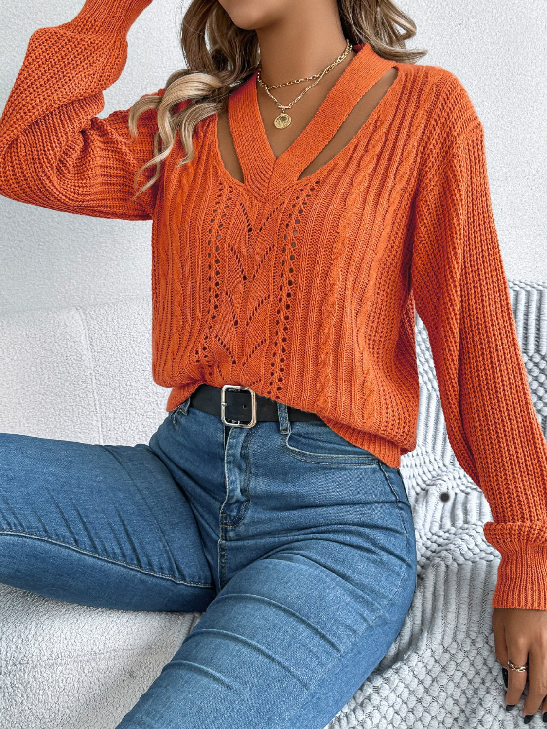 Trendy orange cable knit sweater with a relaxed fit and V-neck cutout