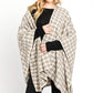 Woman wearing cozy ivory plaid wrap shawl over black top.
