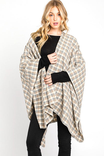 Woman wearing cozy ivory plaid wrap shawl over black top.
