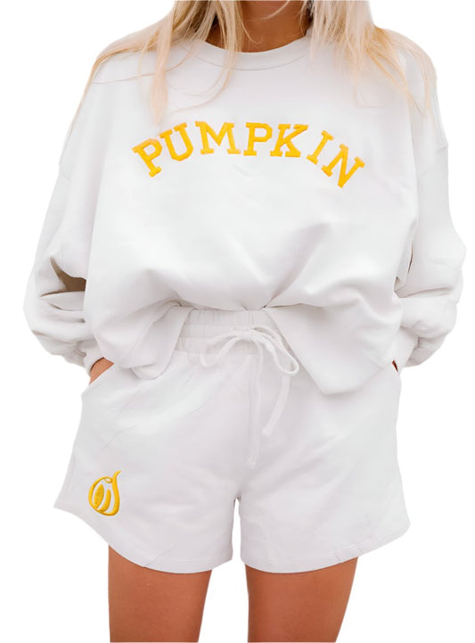 Close-up of a soft white sweatshirt with the word "Pumpkin" in bright orange letters.
